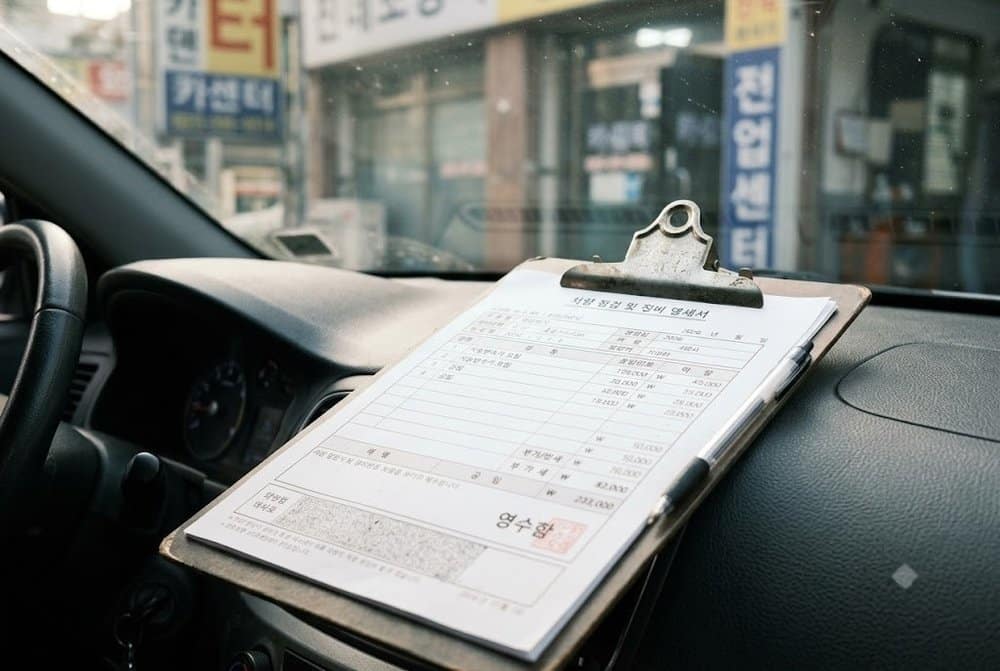 차량 대시보드 위의 정비 명세서와 미션오일 교체비용
